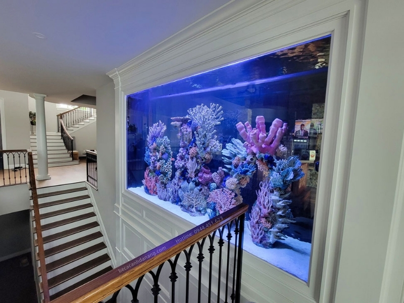 Hồ cá gắn tường có san hô nhiều màu sắc giúp lối lên xuống cầu thang thêm đẹp